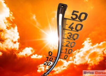 Concept for climate change, heat wave or global warming, orange sky with clouds, bright sun and thermometer