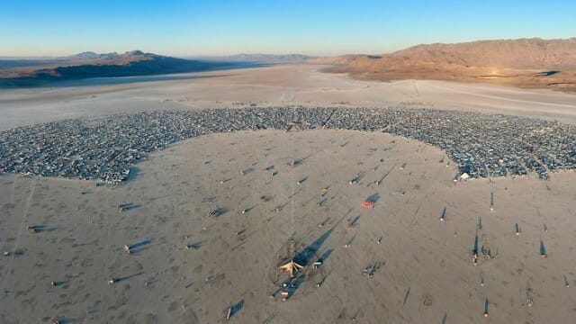 Partecipanti al Burning Man si uniscono tra il fango per mettersi in salvo